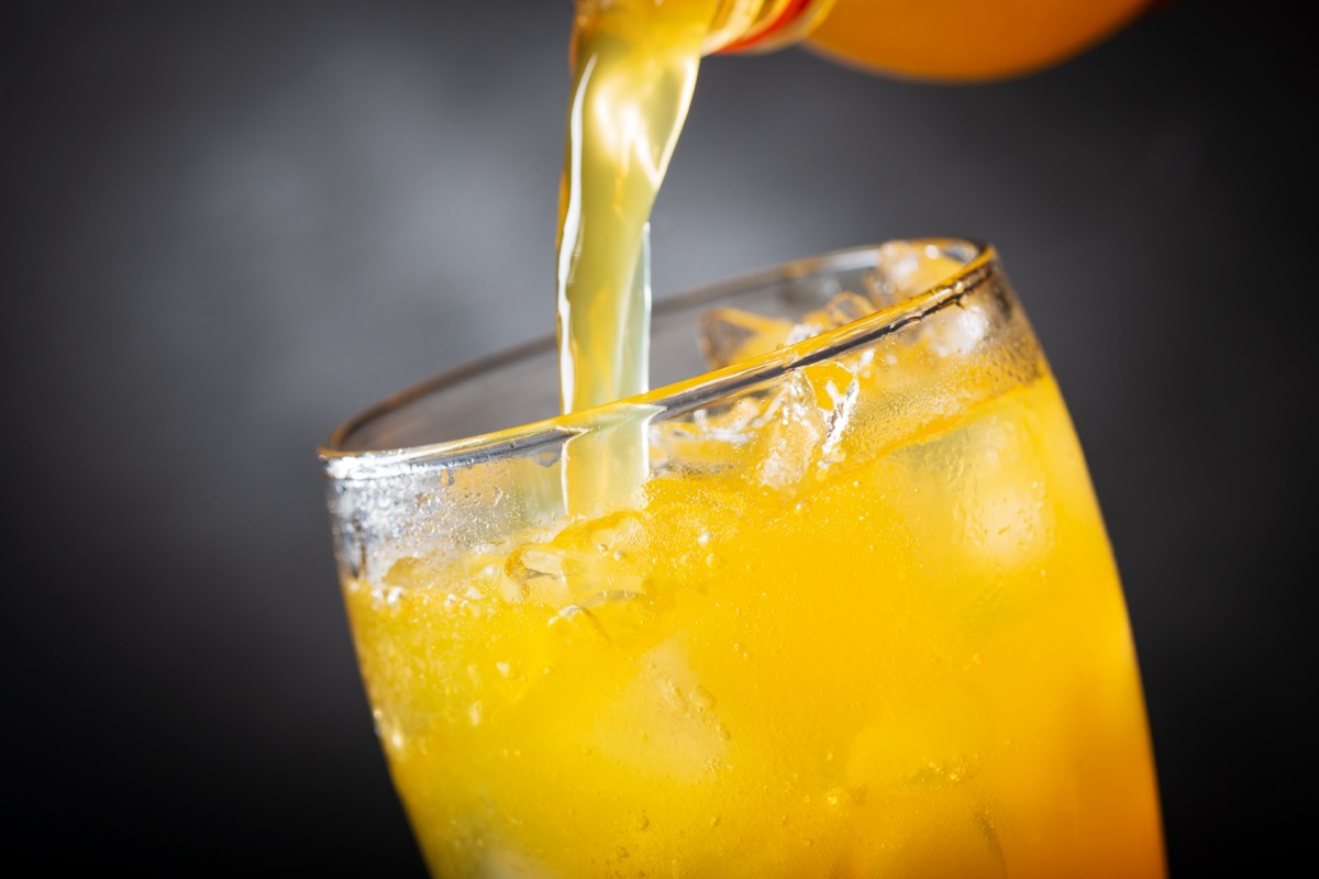 soft drink, pouring orange soda into glass on dark background