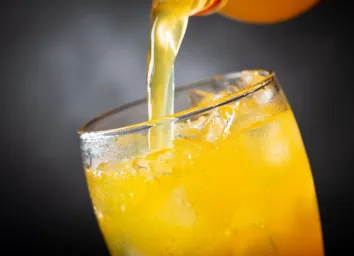 soft drink, pouring orange soda into glass on dark background