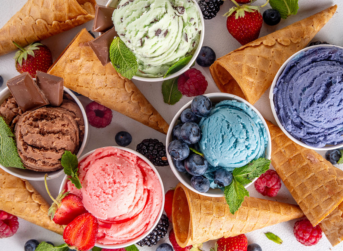 Colorful bright ice cream on bowls, with waffle cones and berries, on white background. Variety of ice cream portions with different flavor with fresh berries top view copy space layout background